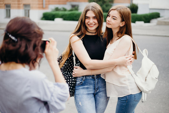 Photography, hobby, leisure, travel, sightseeing, friendship, togetherness. Young woman take picture of her friends using camera at city background