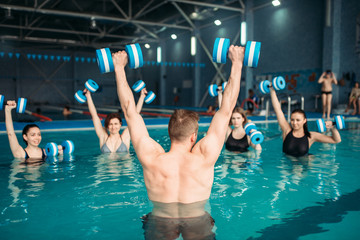 Class with trainer on workout with aqua dumbbells