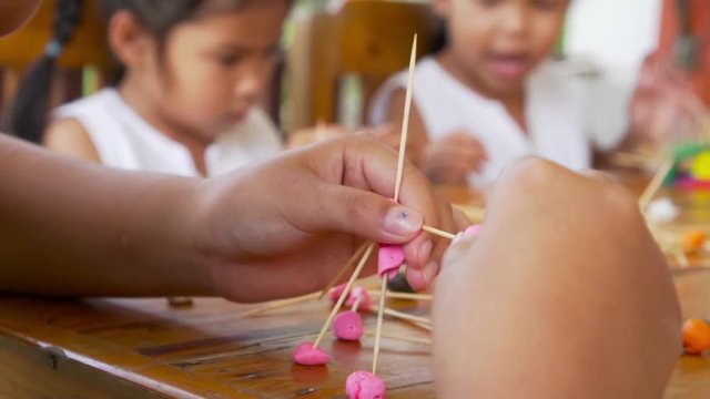 Asian little girl concentrated with play dough building a molecule model in attentive. Recorded video in 60 fps