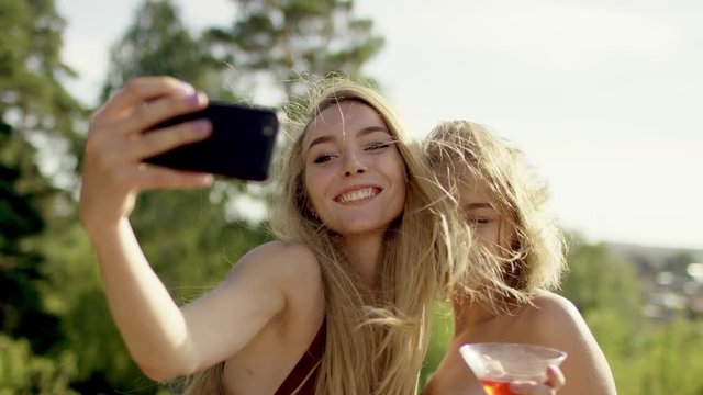 Attractive blonde girls posing and laughing for selfi in swimsuit and bikini a background of nature