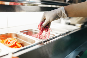 Male cook prepares fresh vegetables for burger