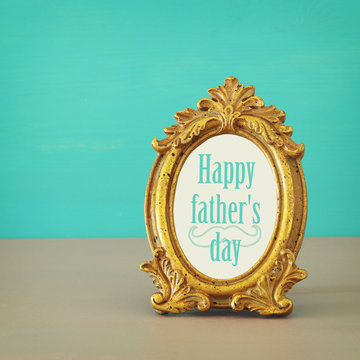 Image of golden vintage frame with text: HAPPY FATHER'S DAY, over wooden table.