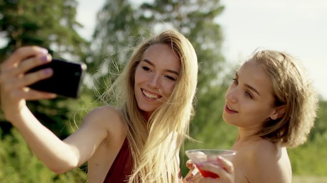 Attractive blonde girls posing and playing with their hair for selfi in swimsuit and bikini a background of nature
