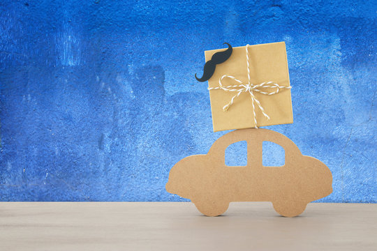 Image of wooden car with gift box on the roof, present for dad. Father's day concept.
