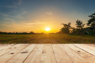 Empty wooden table top and display montage with blur background field sunset.