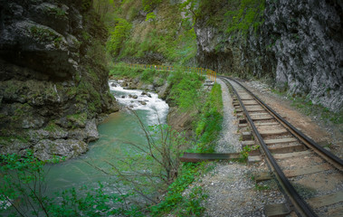 old narrow-gauge railroad under a rock near the mountain river in the gorge, the Guam gorge of Adygea, the Caucasus