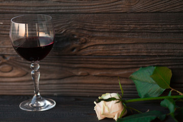 Glass of red wine on wooden table. Sunset light romantic time.