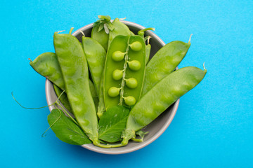 Fresh green ripe green peas in bowl copy space close up isolated on trendy blue background