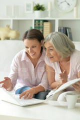 young beautiful woman with mother using laptop