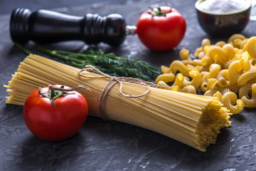 Uncooked pasta cavatappi and spaghetti with ingredients for tomato sauce. Concept of the composition of food design.