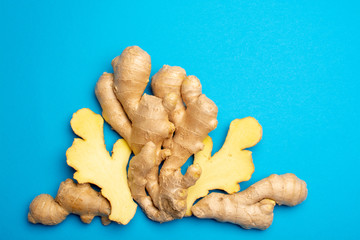 Fototapeta premium Trendy food flat lay concept on blue background with fresh big ginger root close up copy space isolated