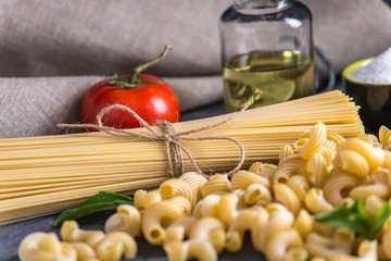 Uncooked pasta cavatappi and spaghetti with ingredients for tomato sauce. Concept of the composition of food design.