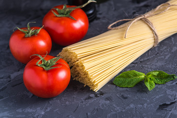 Uncooked pasta spaghetti with ingredients for tomato sauce. Concept of the composition of food design.