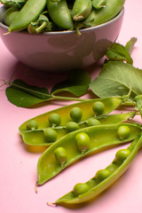 Fresh green ripe sugar snaps, sweet peas in bowl copy space close up on light pink background