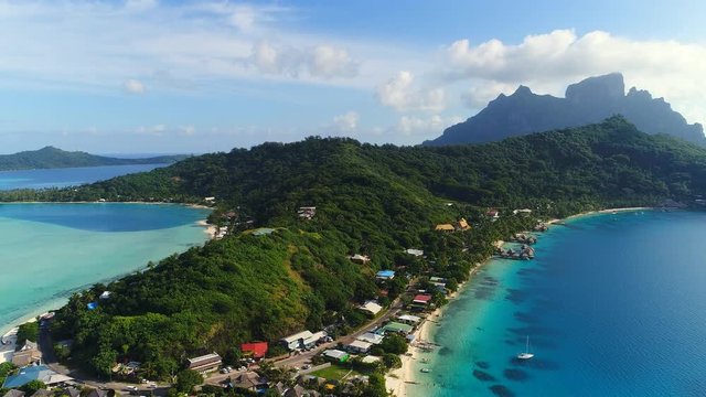 Aerial view of tropical paradise of Bora Bora island, crystal clear water of scenic turquoise blue lagoon, lush green jungle hills - South Pacific Ocean, French Polynesia from above, 4k UHD