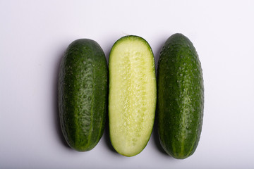 Fresh small green cucumbers whole and sliced close up copy space isolated on white background