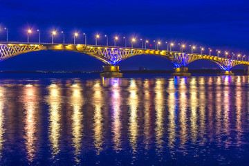 Fototapeta na wymiar an automobile bridge across the Volga River at night, illuminated by the light of lanterns, the light of which is reflected in the river