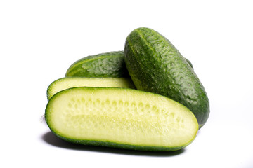 Fresh small green cucumbers whole and sliced close up copy space isolated on white background