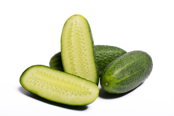 Fresh small green cucumbers whole and sliced close up copy space isolated on white background