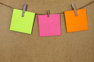 Hojas de papel de color verde, naranja  y rosa (posit), sujeto con unas pequeñas pinzas de colores...
