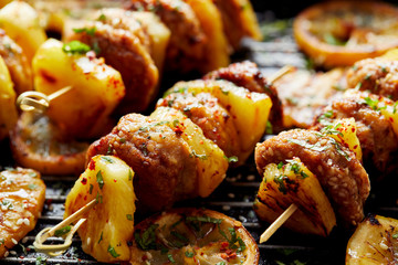 Grilled skewers with chicken meatballs and pineapple with herbs on a grill plate. Fruit and meat skewers