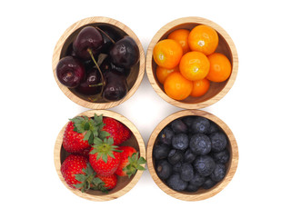 Fresh summer fruits, Cherry, strawberry, cape gooseberry and blueberry in wooden bowl isolated on white background.