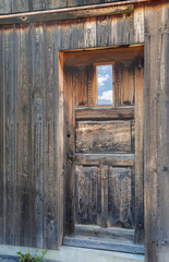 Fototapeta na wymiar weathered old wooden door with sky reflection in window