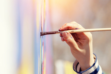 Close-up of girl holding hand brush for painting, drawing, glare of sun