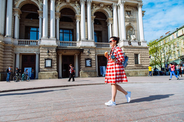 woman walk by center of european city with ice cream and camera. sunny day