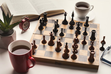 Wooden desk with chess play, book and coffee cup