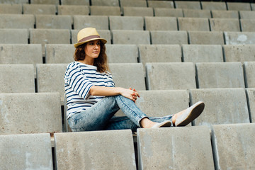 Fototapeta na wymiar Young woman sitting in the amphitheatre in the park alone