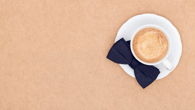 Happy Father's Day Background. Cup of coffee and black bow tie on brown background flat lay. Fathers day still life.