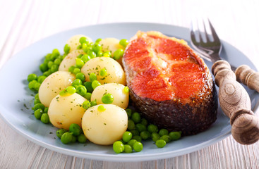 Fried trout steak and young potatoes with peas