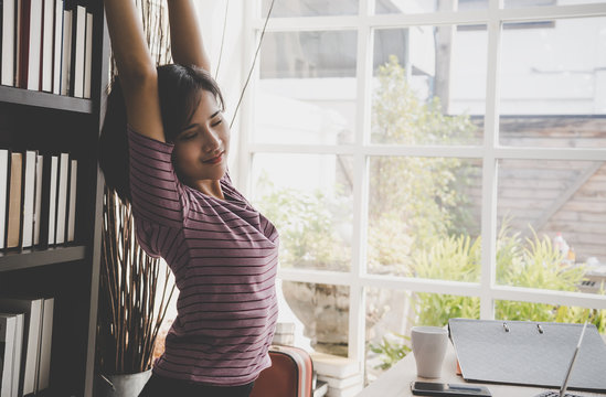 Happy business woman is relaxing and stretching out in office
