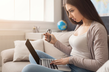 Woman using laptop while sitting on sofa