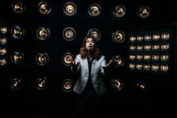 men singer with long hair, with microphone on the stage