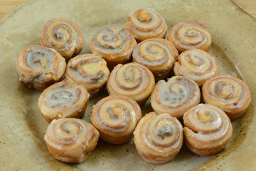 Close up of small cinnamon rolls with icing on ceramic bunch or breakfast party platter