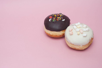 Doughnuts with Chocolate and White Icing on White Plate over Pastel Pink Background. Sweet Dessert Donuts with Copy Paste.