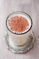 Glass of Milk with Cinnamon or Cocoa Powder with Honney Spoon on rustic background. Healthy Breakfast. Vertical Image.