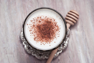 Glass of Milk with Cinnamon or Cocoa Powder with Honney Spoon on rustic background. Healthy Breakfast. Vertical Image.