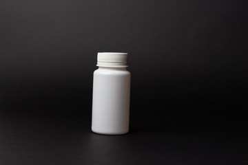 one white pill bottle on black background. treatment