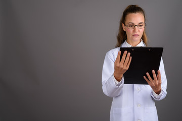 Young beautiful woman doctor against gray background