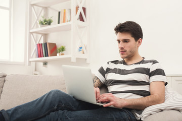 Young man at home messaging online on laptop