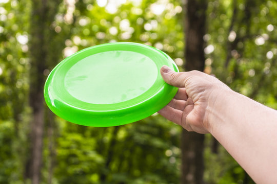 hand throwing a frisbee disc in the park on a summer day