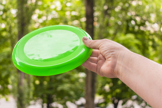 hand throwing a frisbee disc in the park on a summer day