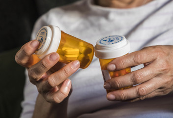 Woman examining medication treatment, several boats in the hand, conceptual image