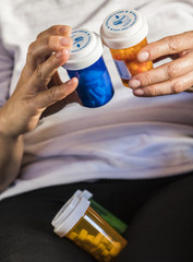 Woman examining medication treatment, several boats in the hand, conceptual image