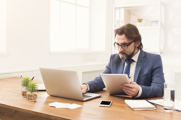 Young smiling man using laptop in modern office