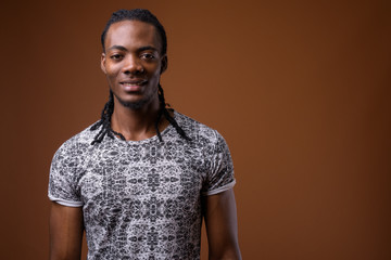 Obraz premium Young handsome African man against brown background