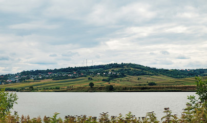 A typical natural landscape in the country of Suceava: fields, a small lake and mountains on the horizon, Romania.